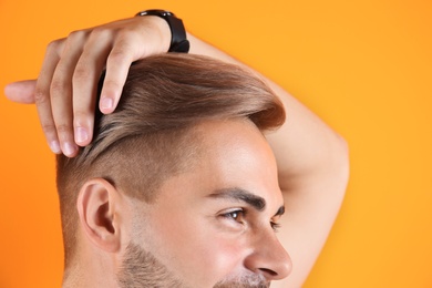 Photo of Young man with trendy hairstyle on color background, closeup