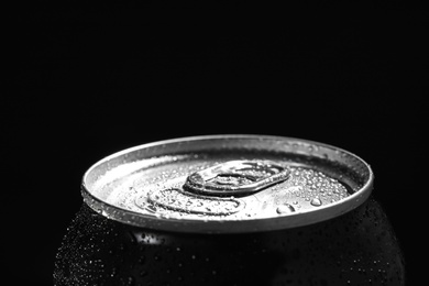 Photo of Aluminum can of beverage covered with water drops on black background. Space for text