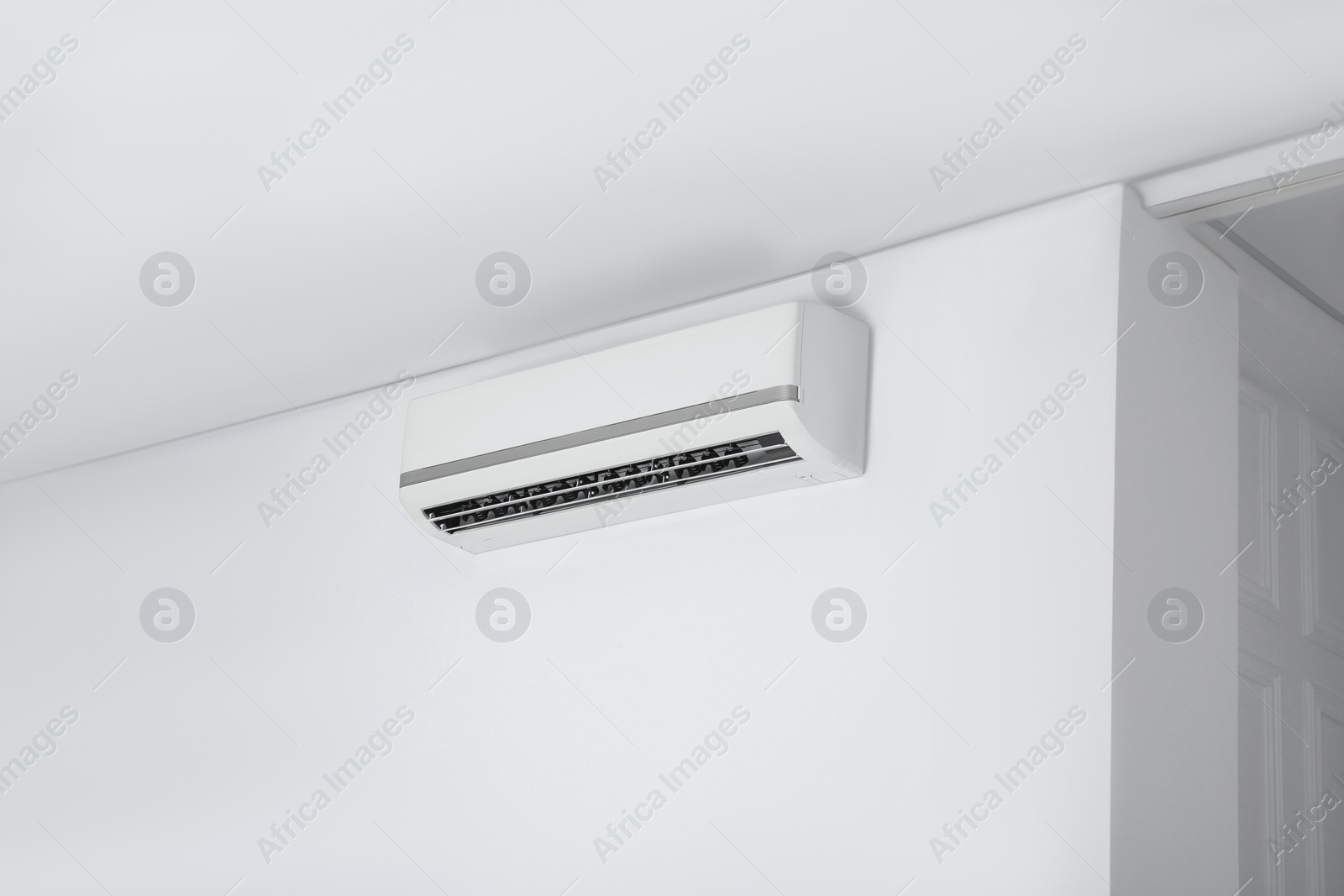 Photo of Modern air conditioner on white wall indoors. Space for text