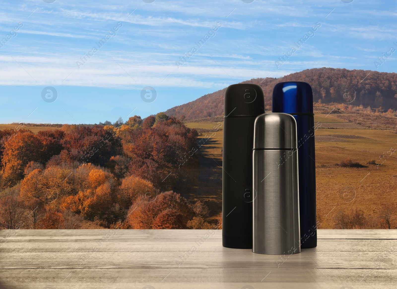 Image of Wooden desk with thermoses and mountain landscape on background