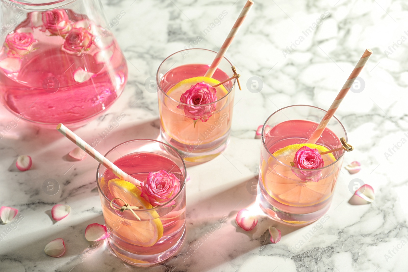 Photo of Refreshing drink with lemon and rose on white marble table