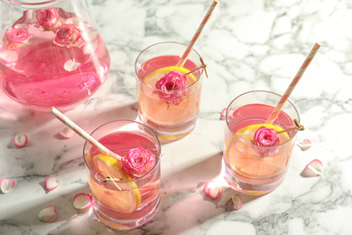 Photo of Refreshing drink with lemon and rose on white marble table