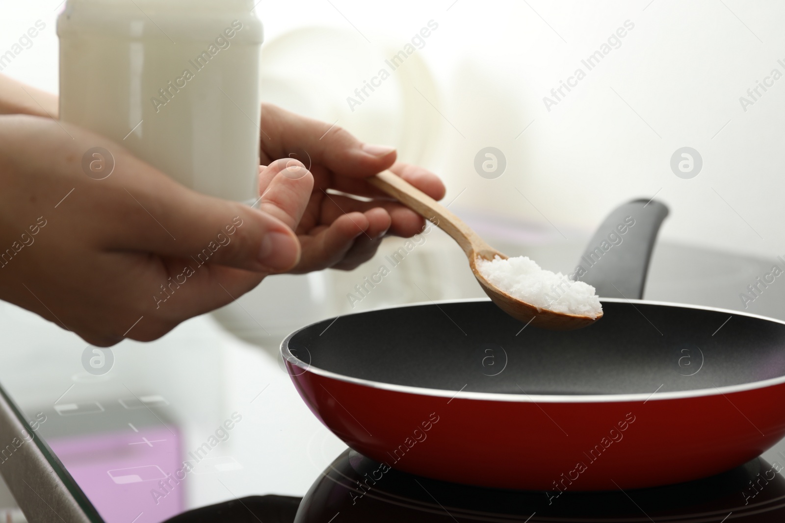 Photo of Woman cooking with coconut oil on induction stove, closeup