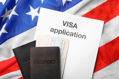 Photo of Flat lay composition with passports and visa application on flag of USA