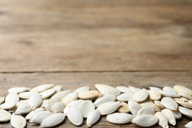 Photo of Raw pumpkin seeds on wooden background, space for text. Vegetable planting