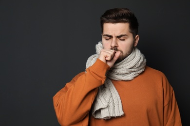 Photo of Handsome young man coughing against dark background. Space for text