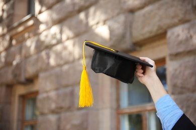 Photo of Student with graduation hat outdoors, closeup. Space for text
