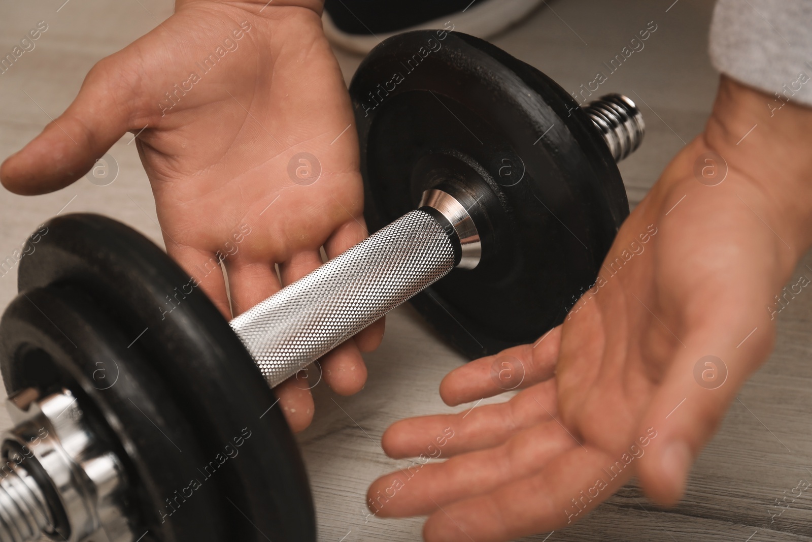 Photo of Athlete taking dumbbell indoors, closeup. Suffering from calluses on hand