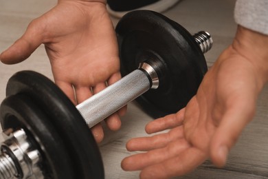 Athlete taking dumbbell indoors, closeup. Suffering from calluses on hand