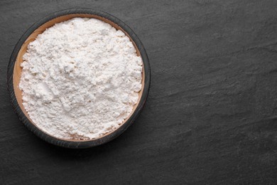 Photo of Bowl with bean flour on black table, top view. Space for text