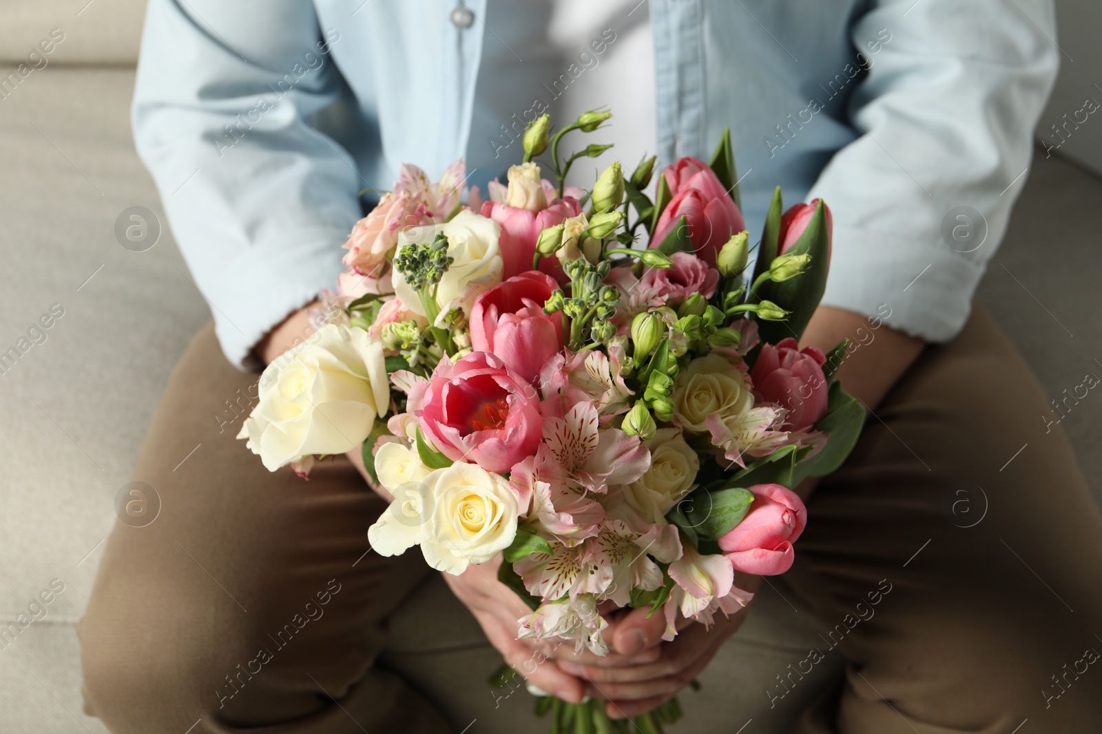 Photo of Man holding bouquet of beautiful flowers indoors, closeup