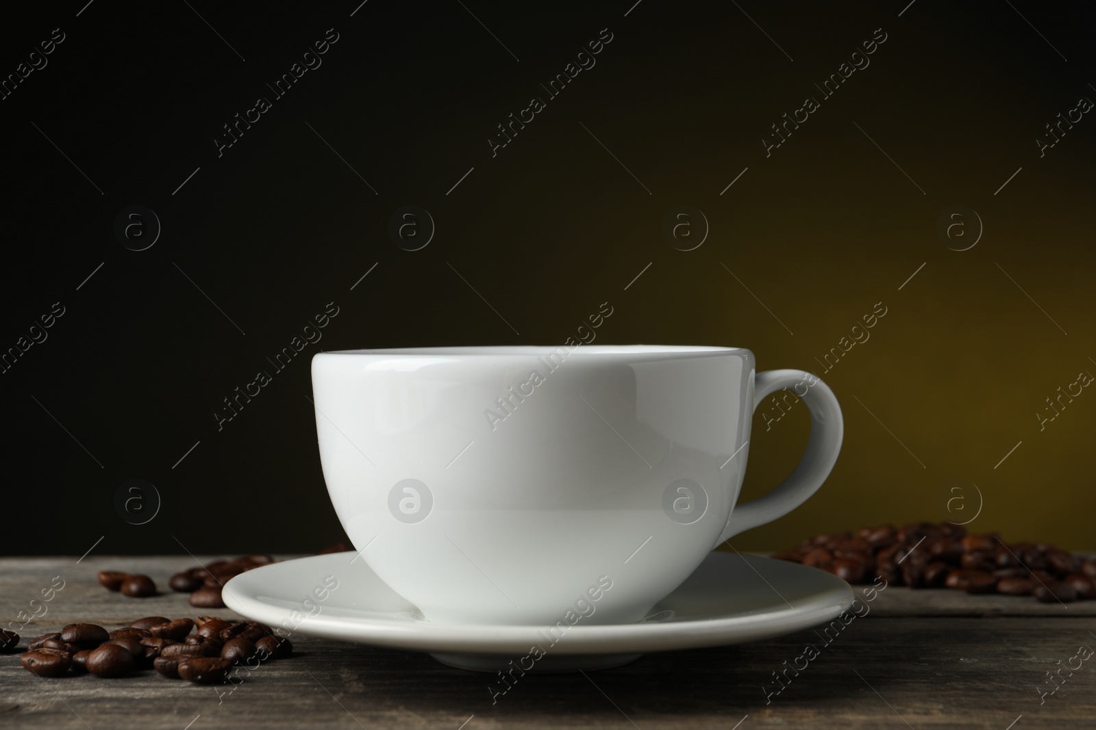 Photo of Cup of hot aromatic coffee and roasted beans on wooden table