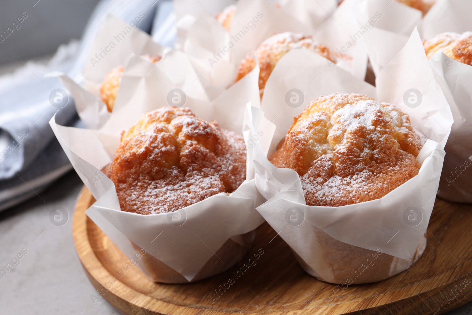 Photo of Delicious muffins with powdered sugar on table, closeup