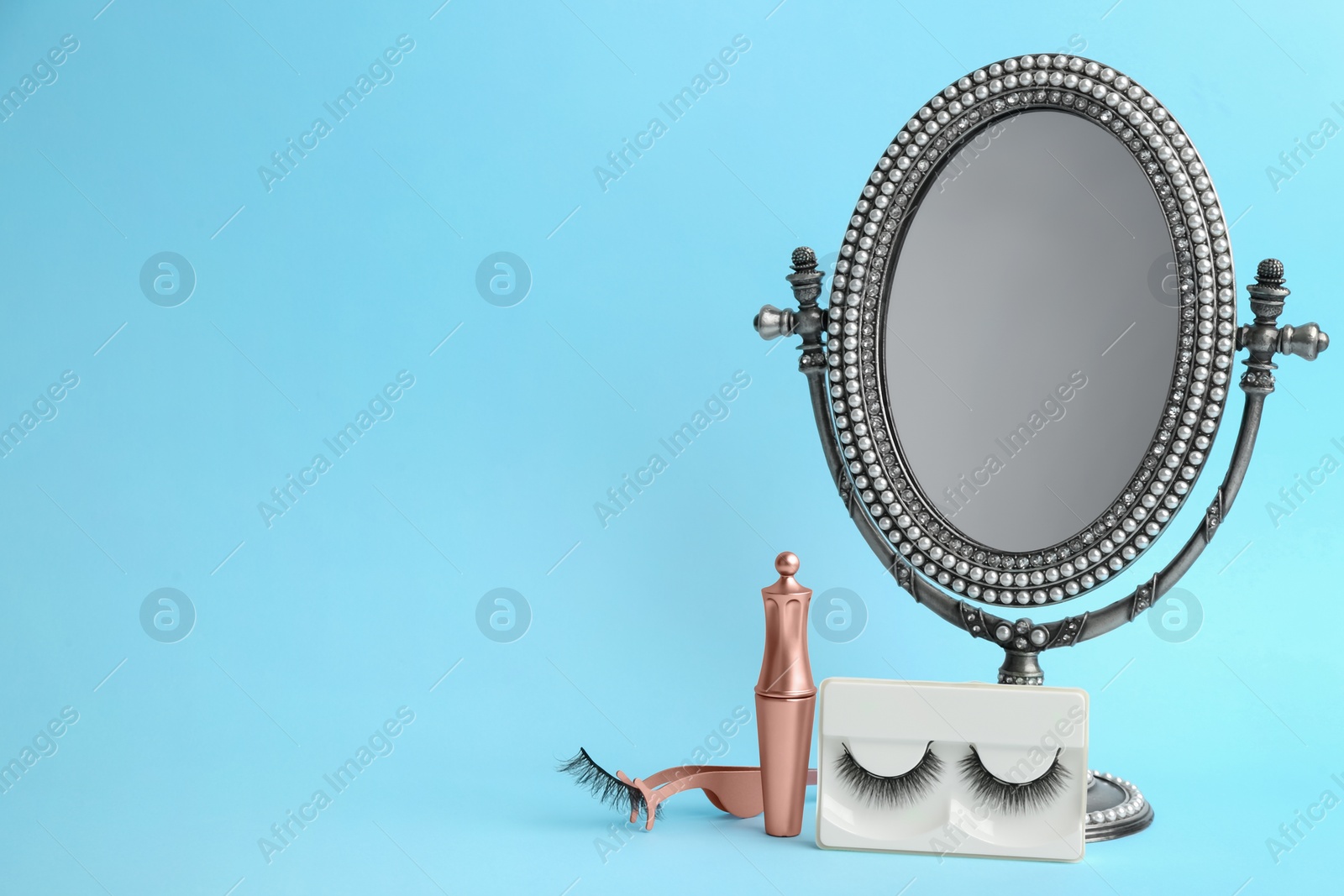 Photo of Magnetic eyelashes and accessories on light blue background. Space for text