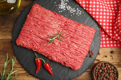 Photo of Raw fresh minced meat and other ingredients on wooden table, flat lay