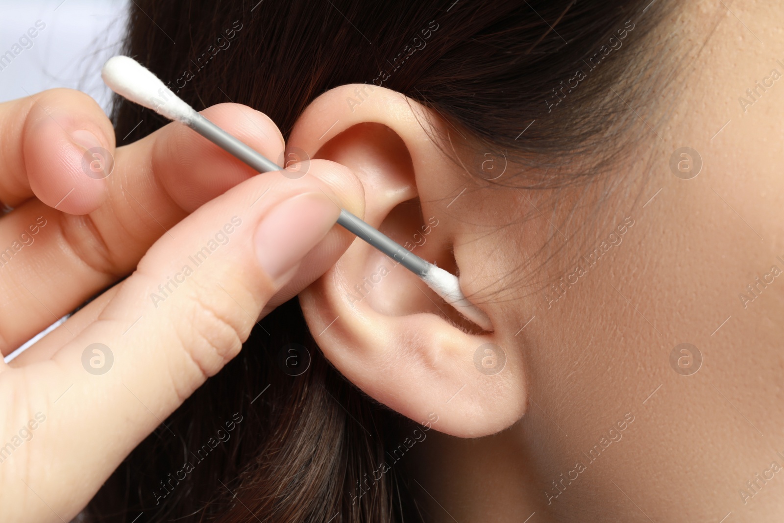 Photo of Woman cleaning ear with cotton swab, closeup