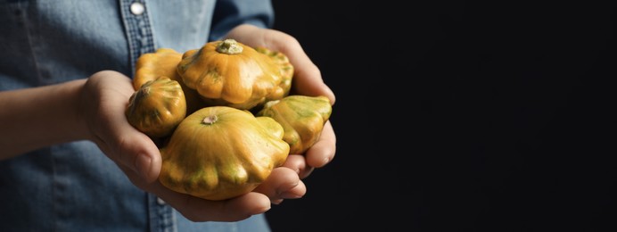 Image of Woman with fresh pattypan squashes on black background, closeup with space for text. Banner design