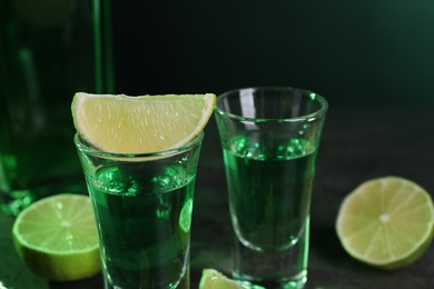 Photo of Absinthe in shot glasses and lime on table, closeup. Alcoholic drink