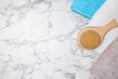 Fresh towels and brush on white marble table, flat lay with space for text