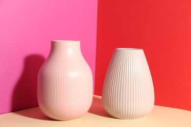 Photo of Stylish empty ceramic vases on color background