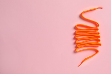 Photo of Orange shoelace on pink background, top view. Space for text