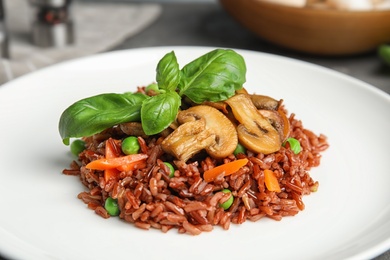 Plate of tasty brown rice with vegetables and mushrooms, closeup