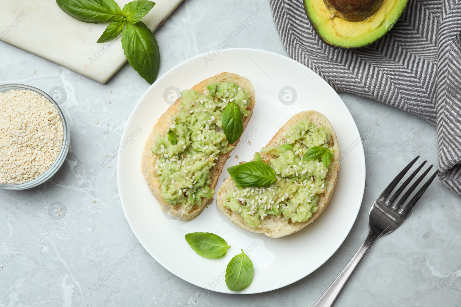 Photo of Plate with delicious avocado sandwiches on grey table, flat lay