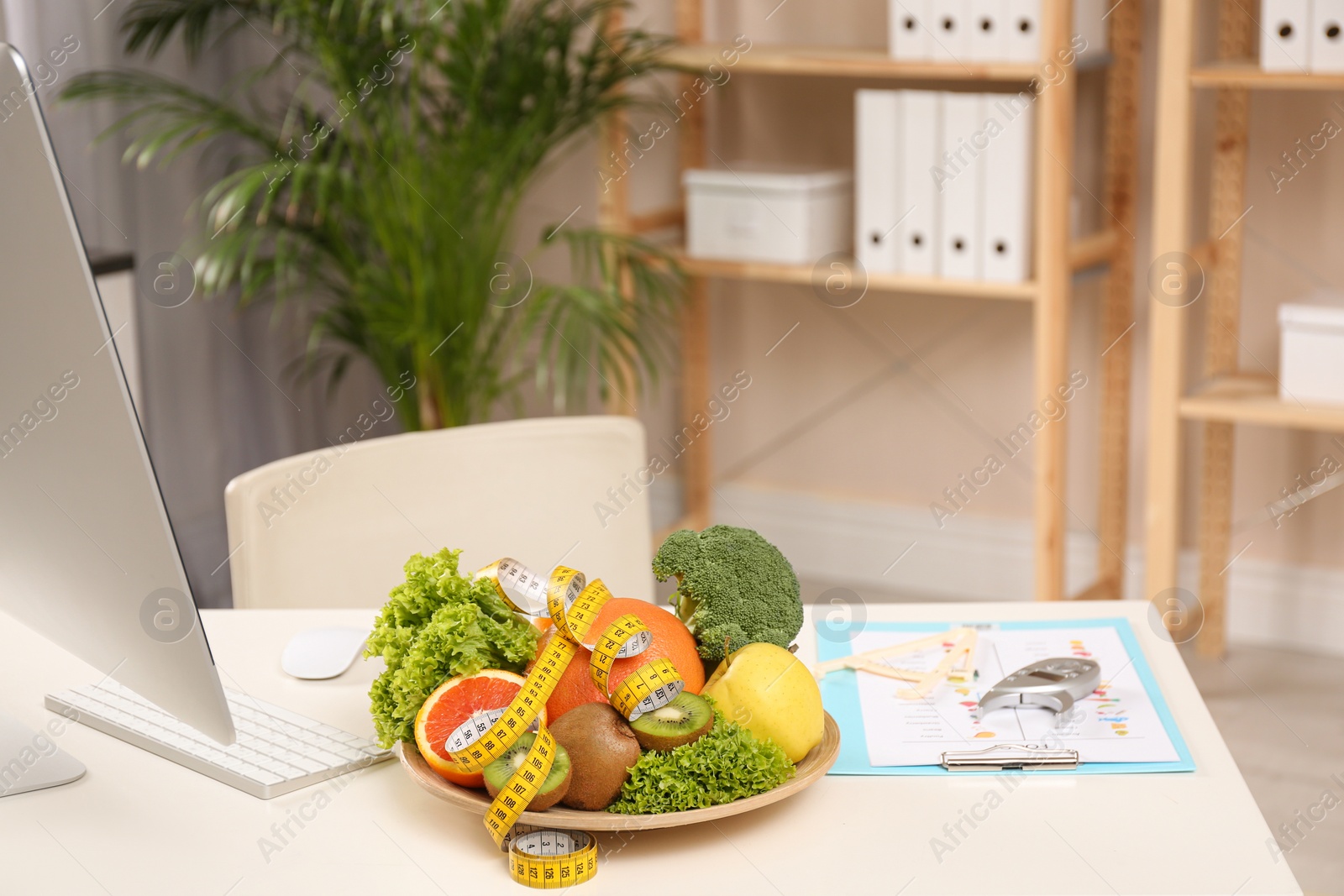 Photo of Nutritionist's workplace with fruits, vegetables, measuring tape and body fat calipers on table