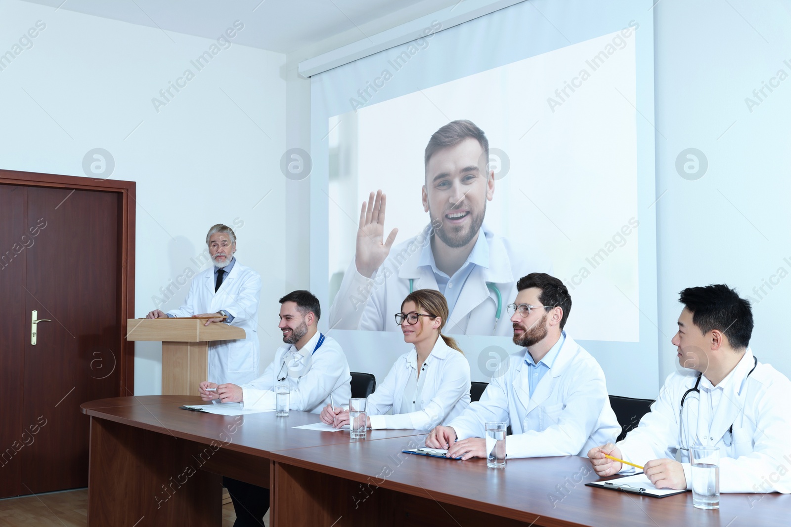 Image of Lecture with online participant. Doctors in meeting room. Using projector for videoconference