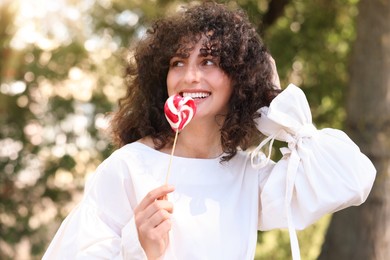 Beautiful woman in white blouse with lollipop outdoors