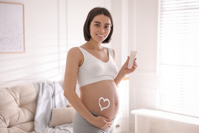 Photo of Young pregnant woman with cosmetic product at home