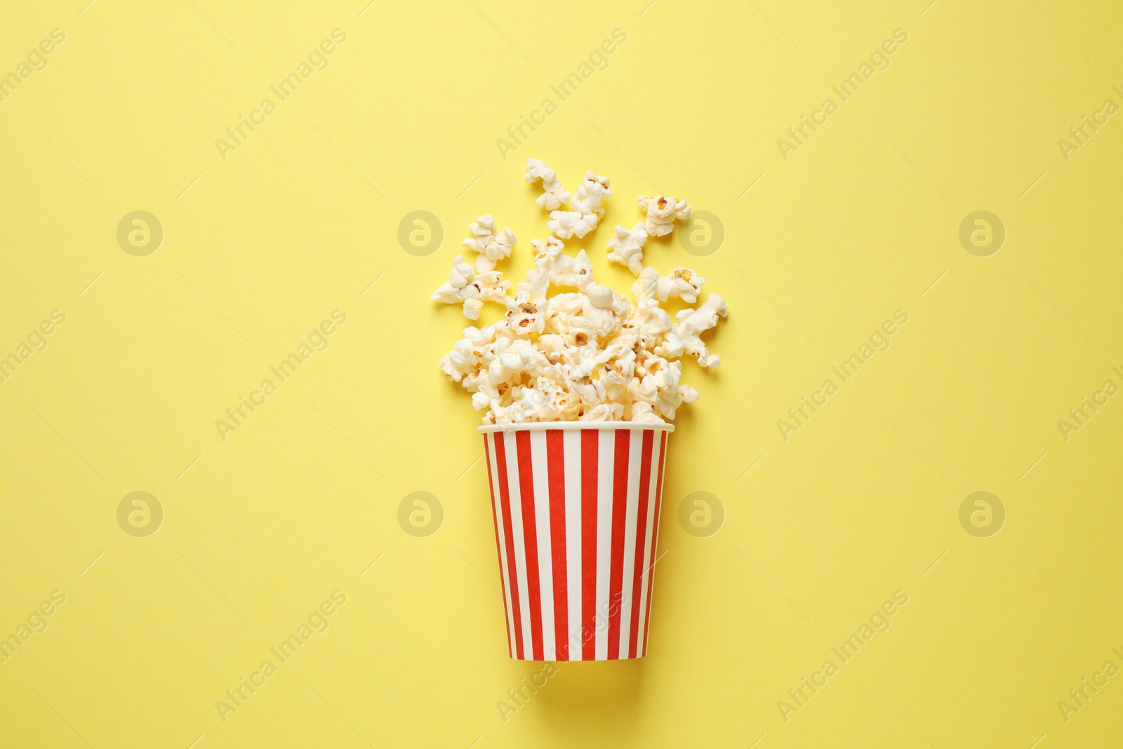 Photo of Delicious popcorn on yellow background, top view