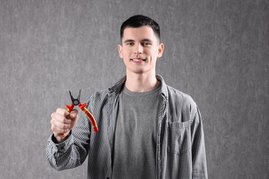 Photo of Young man holding pliers on grey background