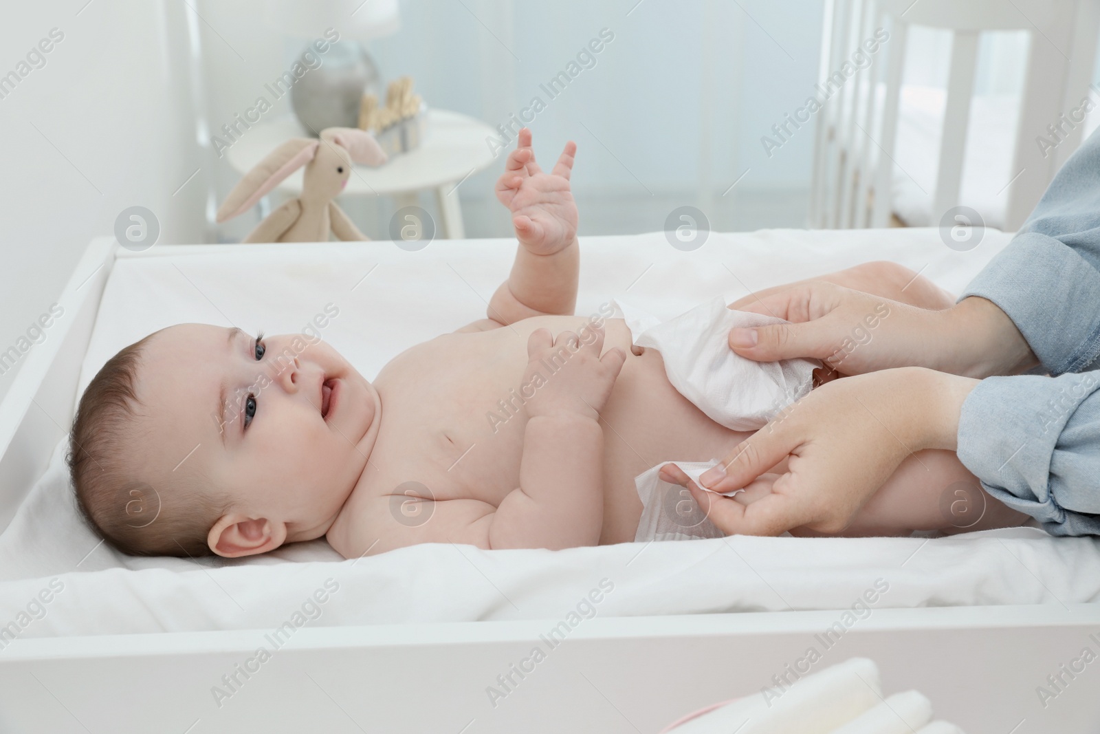 Photo of Mother changing baby's diaper on table at home