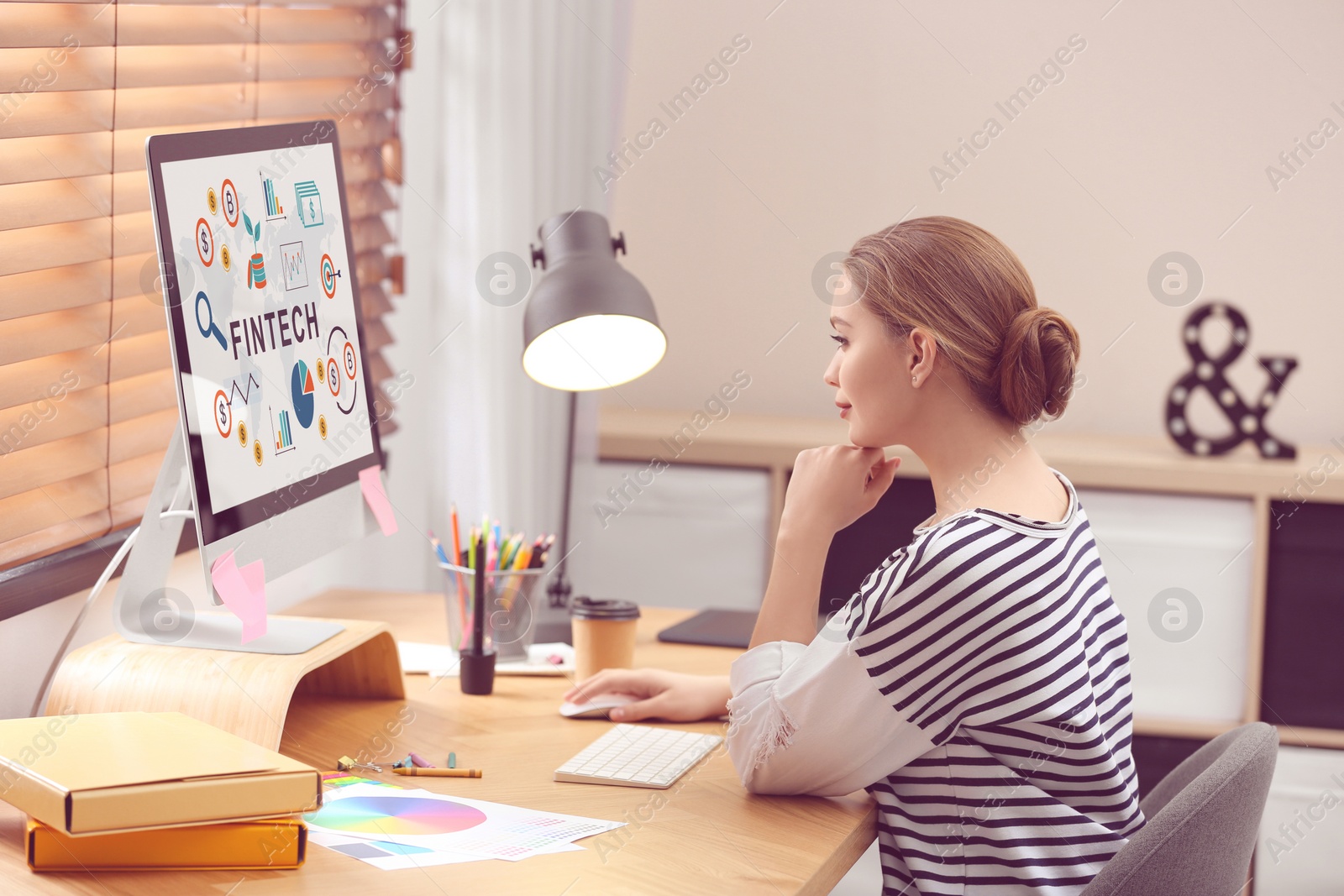 Image of Young woman working on computer with word FINTECH in office