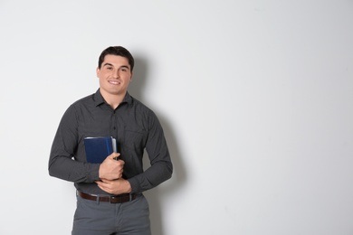 Portrait of male teacher with notebooks on light background