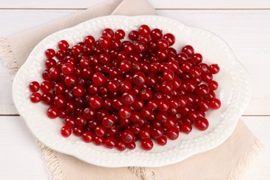 Photo of Plate with ripe red currants on white wooden table, above view