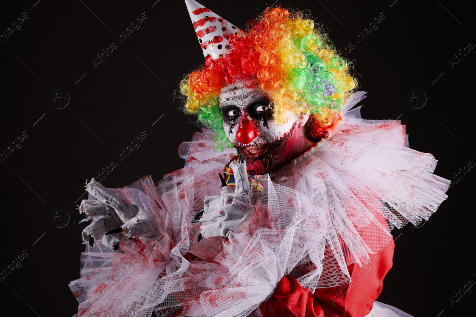 Photo of Terrifying clown on black background. Halloween party costume