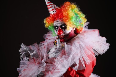 Photo of Terrifying clown on black background. Halloween party costume