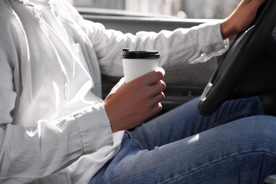 Photo of Coffee to go. Man with paper cup of drink driving his car, closeup