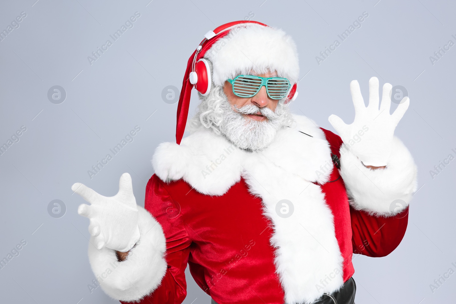 Photo of Santa Claus listening to Christmas music on color background