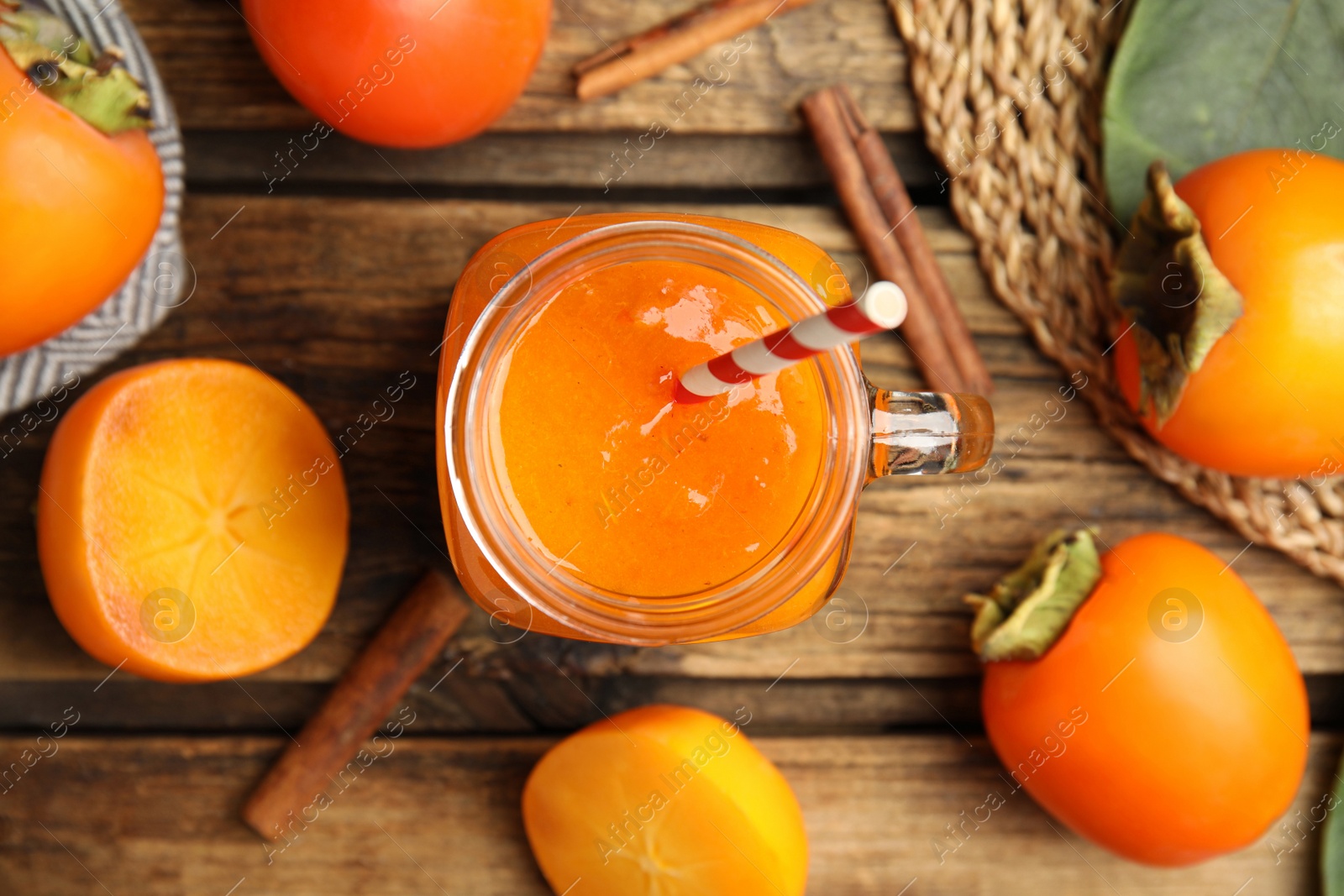 Photo of Tasty persimmon smoothie with straw on wooden table, flat lay