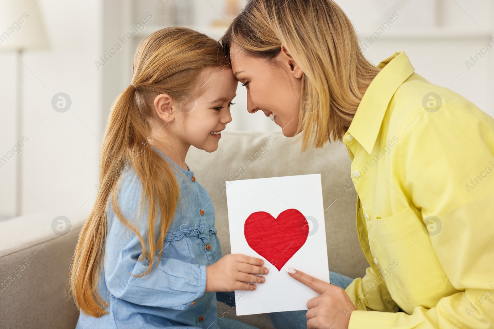 Photo of Little daughter congratulating her mom with greeting card at home. Happy Mother's Day