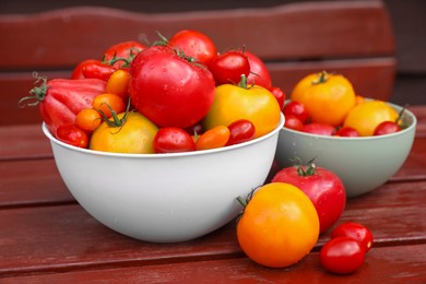 Photo of Bowls with fresh tomatoes on wooden table