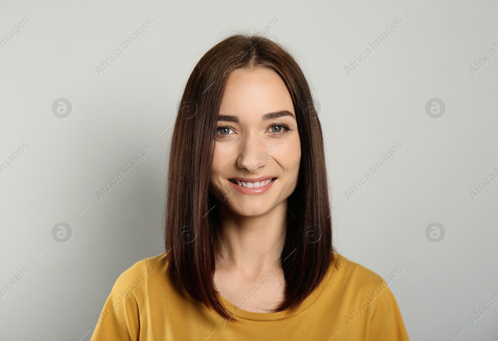 Photo of Portrait of pretty young woman with gorgeous chestnut hair and charming smile on light grey background