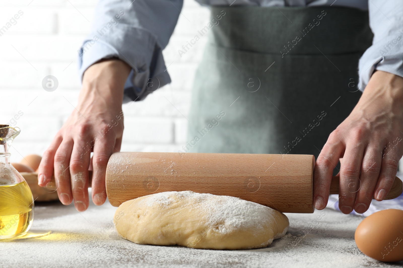 Photo of Woman rolling raw dough at table, closeup