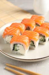 Photo of Tasty sushi rolls and chopsticks on grey table, closeup