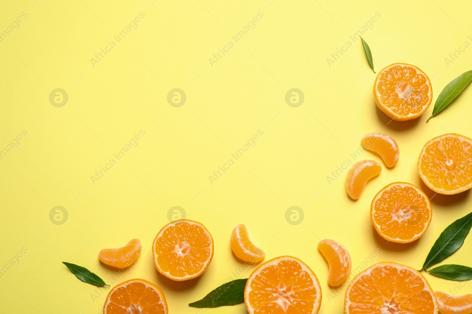 Photo of Flat lay composition with fresh ripe tangerines and leaves on light yellow background, space for text. Citrus fruit