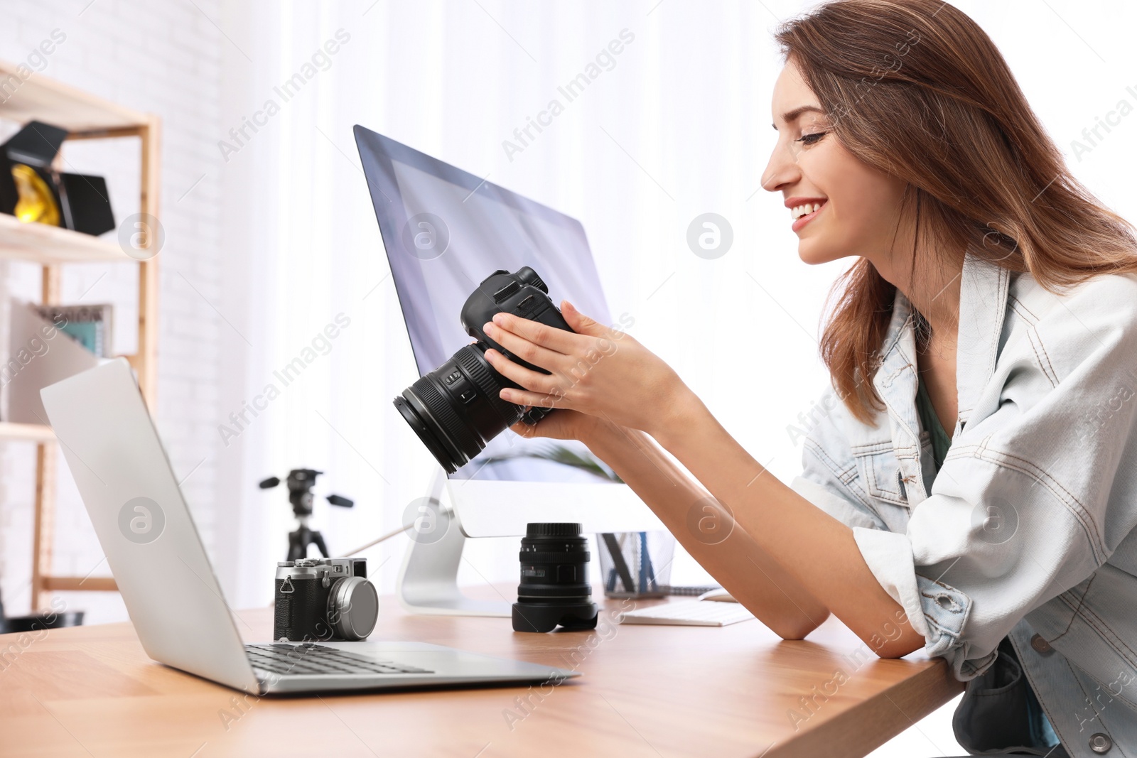 Photo of Professional photographer with camera working at table in office