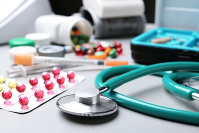 Photo of Stethoscope and pills on grey table. Medical objects